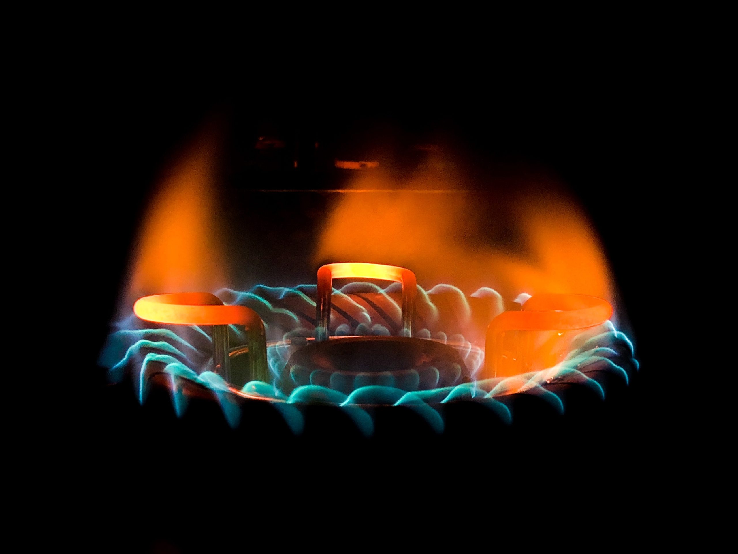 A closeup shot of a beautiful blue-green flame in a gas stove
